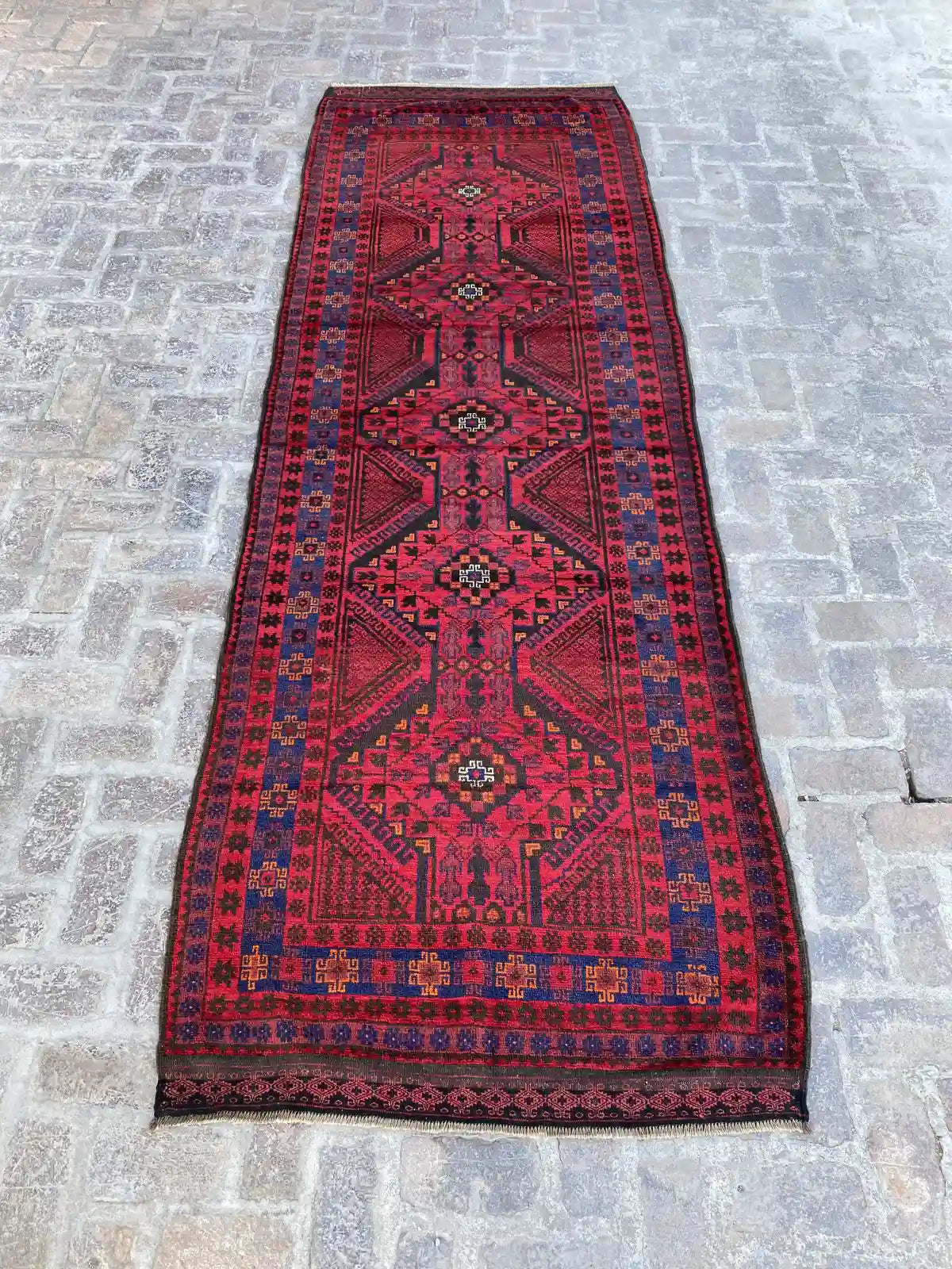 "Hand-knotted Afghan Belouchi rug runner with a bold red background, blue tribal and geometric motifs, measuring 4'1" x 12'2".