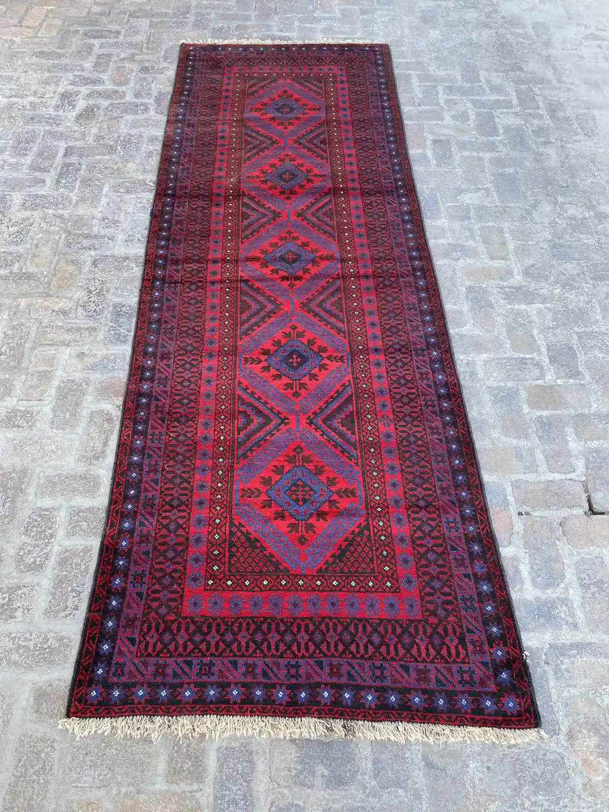 Hand-knotted Afghan Belouchi rug runner with vibrant red background, blue and yellow geometric tribal patterns, measuring 4'0" x 12'3