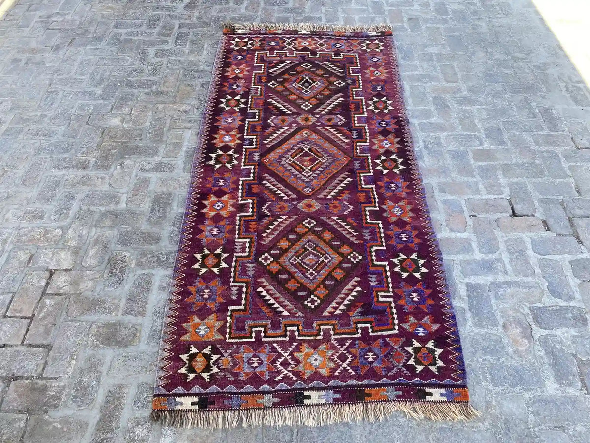 "Handwoven Afghan Kilim rug with a deep purple background and bold multicolor tribal patterns, measuring 4'6" x 9'4"