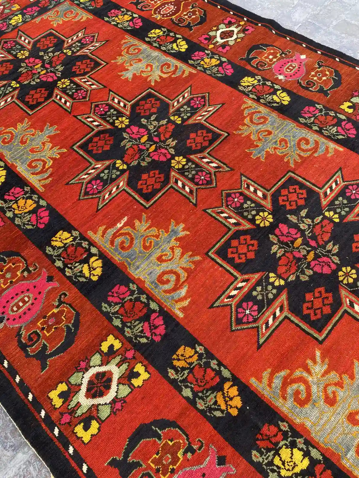 Vibrant hand-knotted Caucasian rug with rich orange and black hues, intricate floral motifs, and geometric patterns,