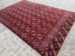 Lovely deep red hand-knotted Turkoman rug with multi-color medallions and geometric border details, measuring 6.9 x 10.9 feet.