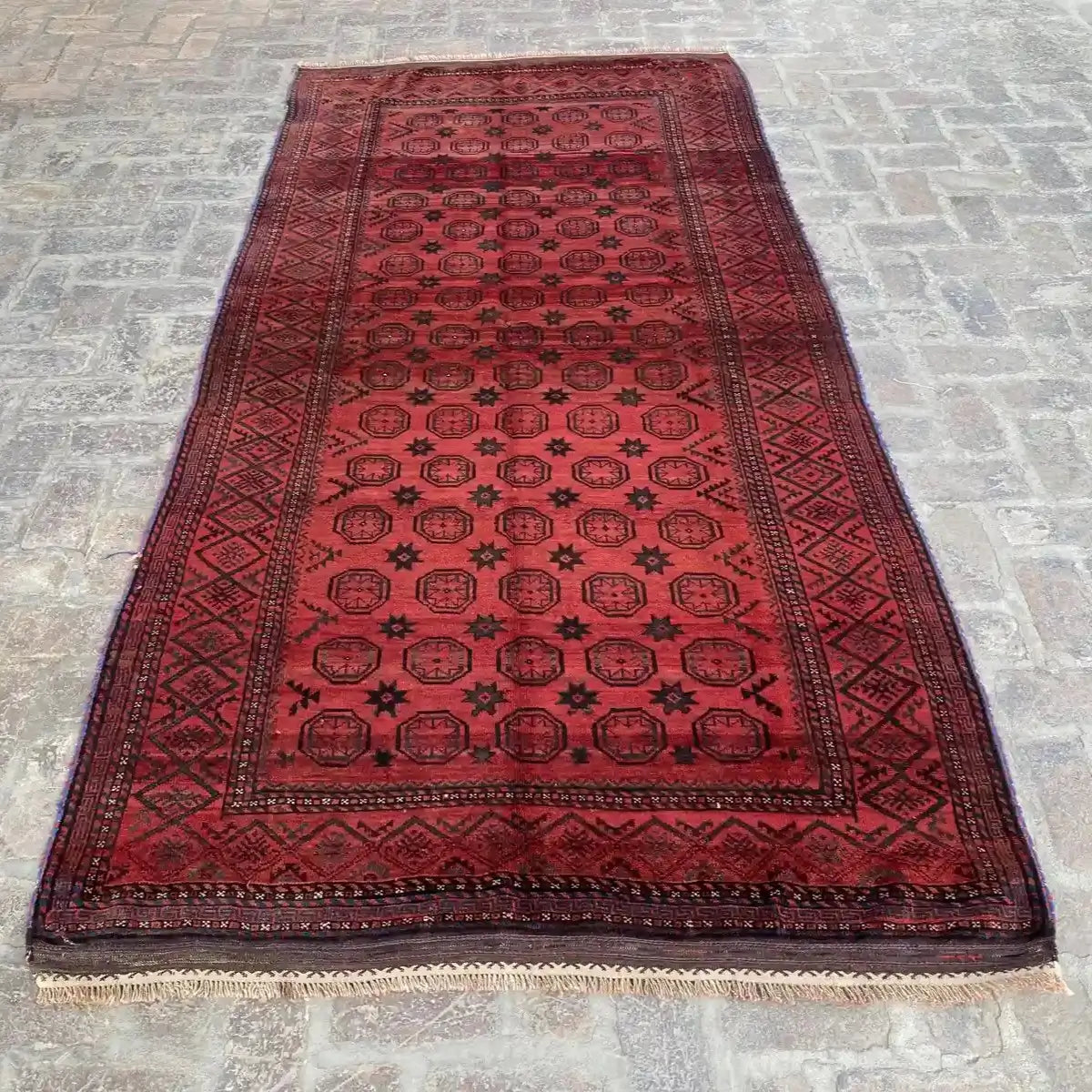 Rich red elegant embroidered Afghan rug, with geometric black star patterns, measuring 5 feet by 10.2 feet.