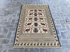 "Handwoven Afghan Soumak Kilim rug with a beige background, animal patterns, and geometric motifs, measuring 4'3" x 6'6"